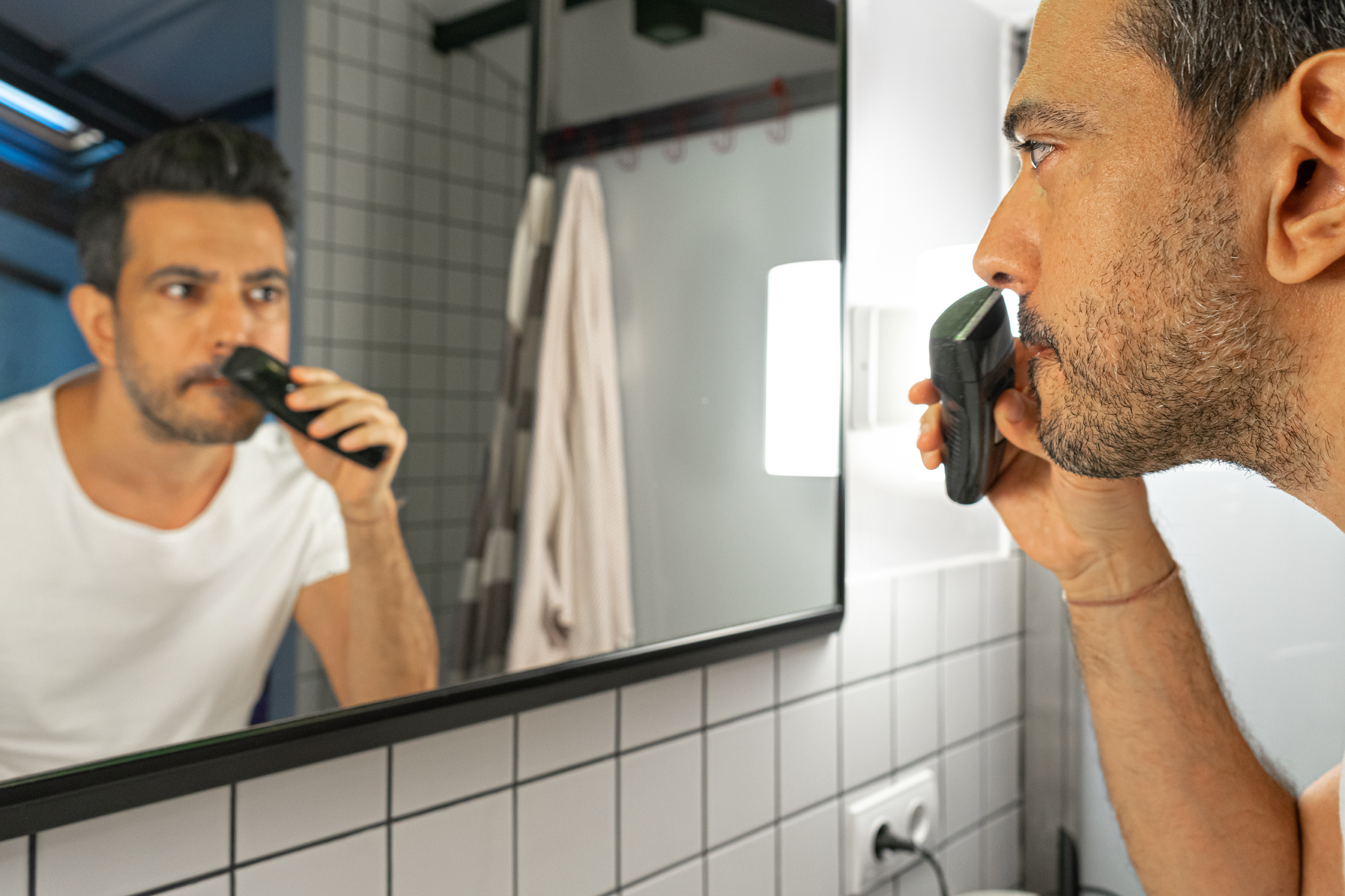 Muž si před zrcadlem zastřihuje vousy