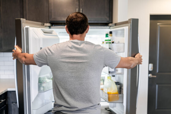 Muž stojí u otevřené lednice