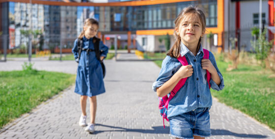 Děti s batohy jdou ze školy.