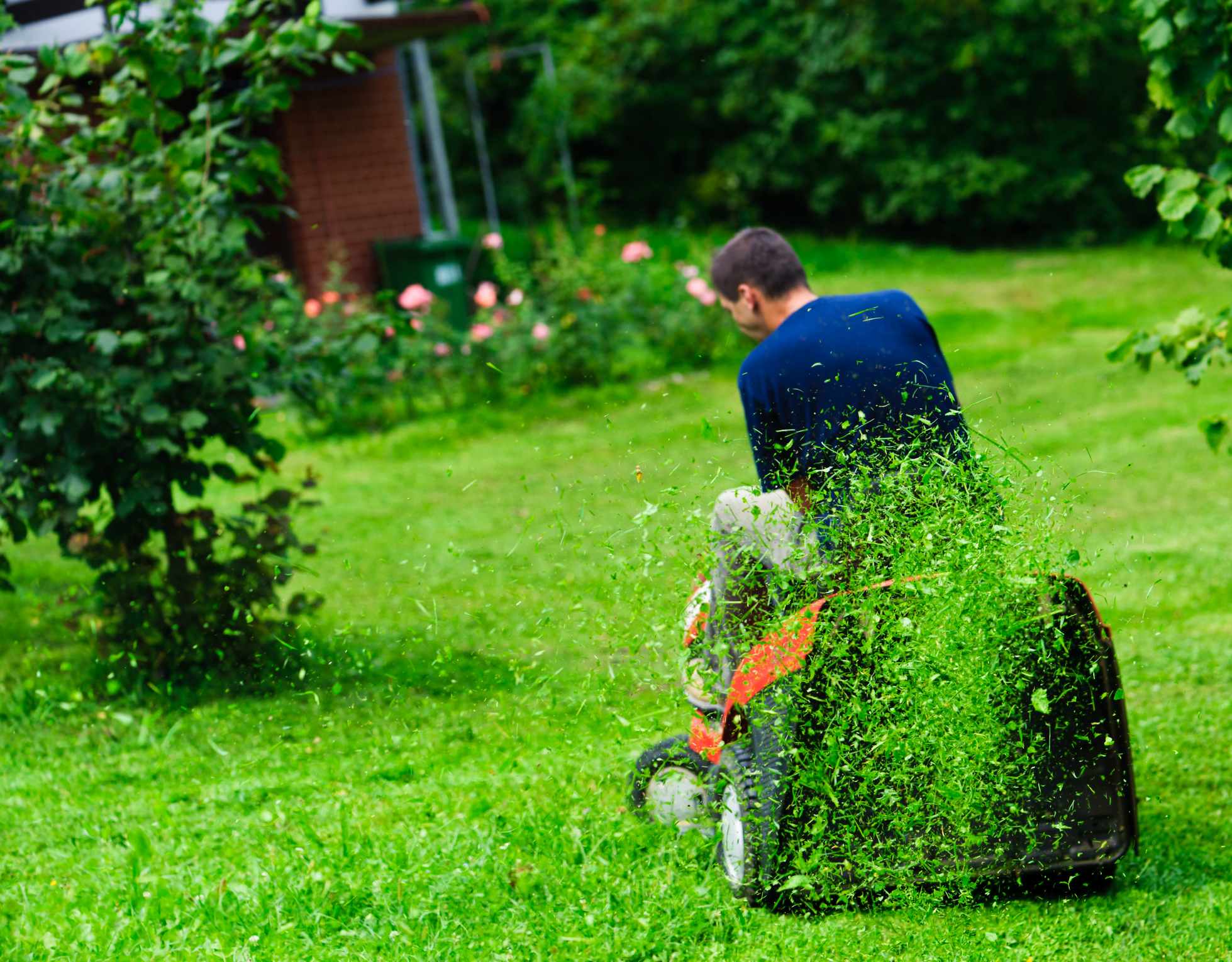 Muž jede na zahradním traktoru a mulčuje trávu