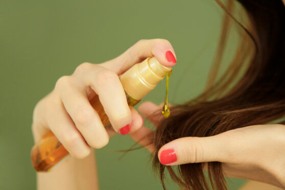 Žena nanáší olej na konce vlasů