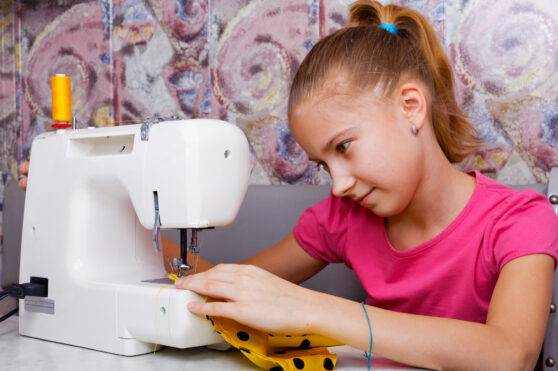 Dívka pracuje na šicím stroji