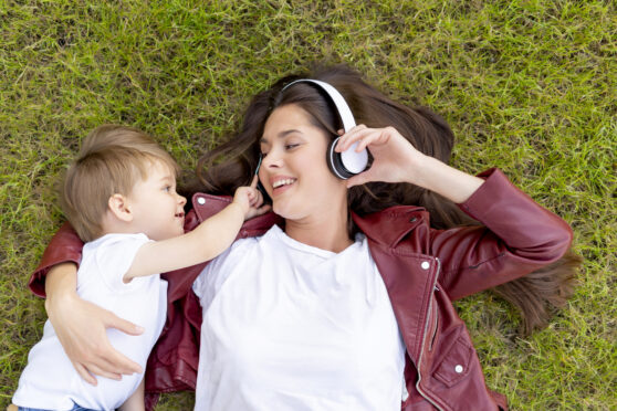 Žena s dítětem a sluchátky v trávě