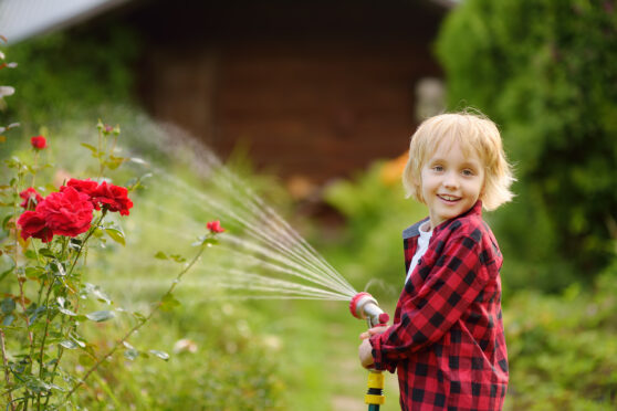 Dítě zalévá zahradu hadicí