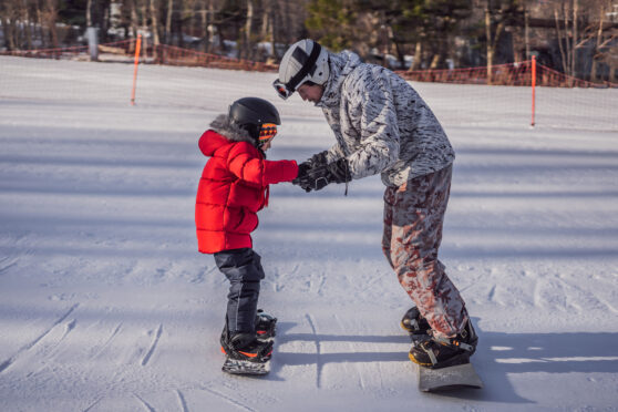 Otec učí dceru na snowboardu