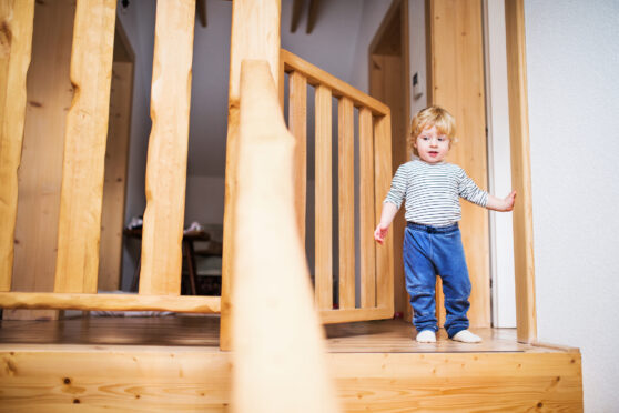Dítě jde ke schodům, v dálce otevřená schodišťová zábrana