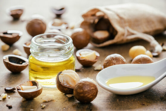Makadamový olej a ořechy na dřevěné desce