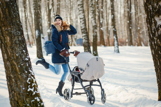 Maminka na zimní procházce s kočárkem