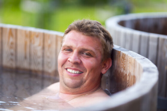 Muž se koupe v dřevěné kádi